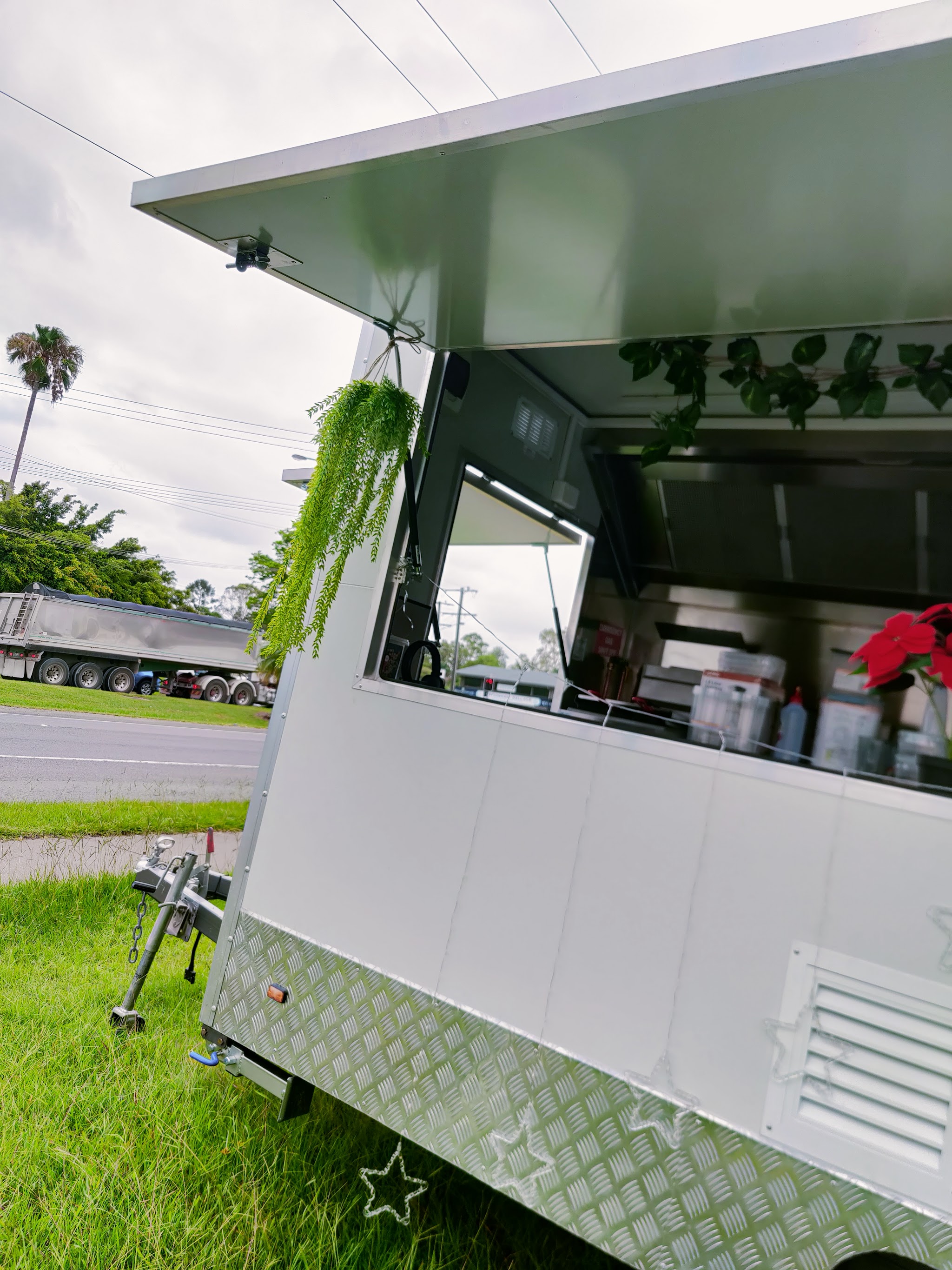 The Momo Gadii trailer window with hanging greenery and a red poinsettia